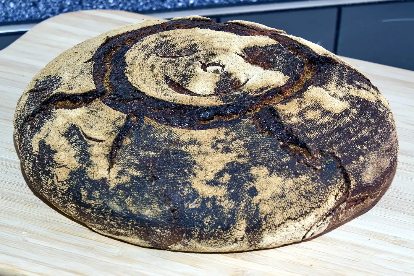 A round loaf of sourdough bread dusted with flour on a wooden board. The photo was not taken in Cary.