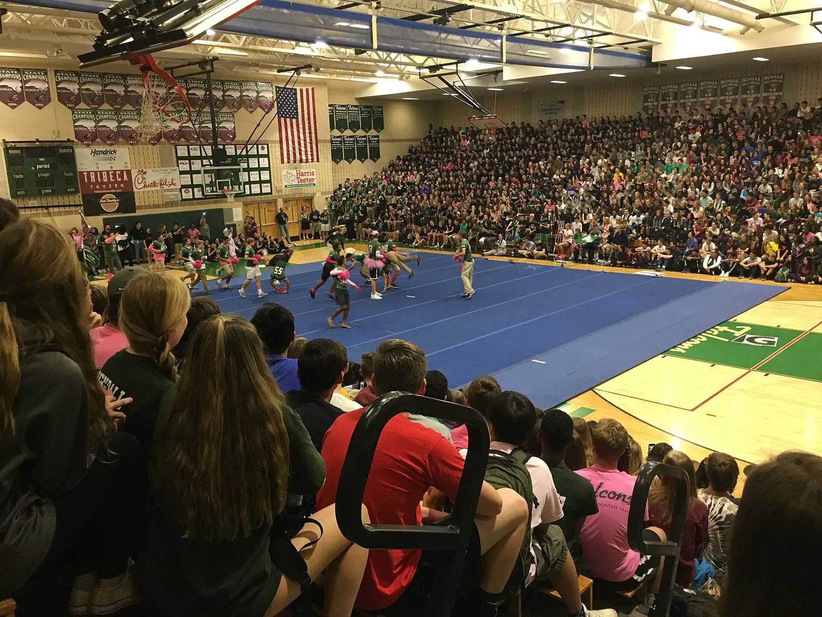 Football players in green jerseys perform for a packed gym at a Green Hope High School pep rally in Cary.