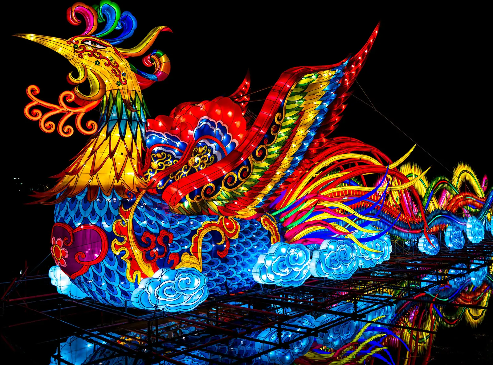 A lit phoenix lantern reflected in the lake at the North Carolina Chinese Lantern Festival at Koka Booth Amphitheatre in Cary.
