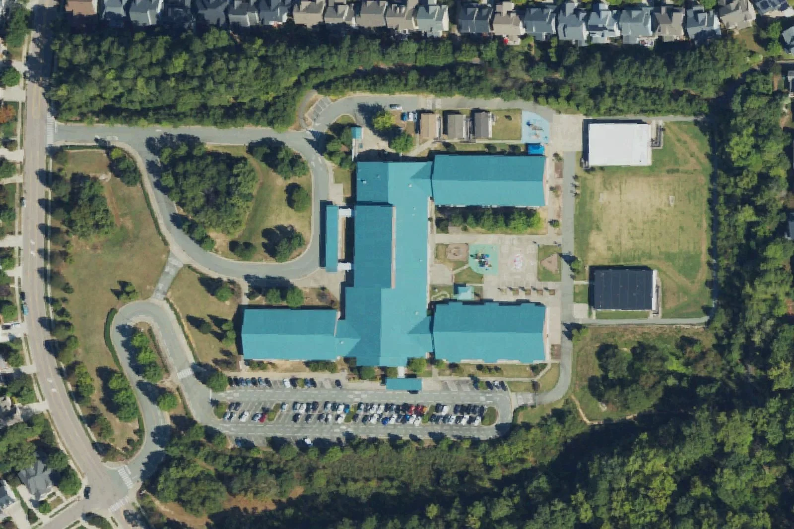 Highcroft Drive Elementary School's blue-roofed building and parking lot on Highcroft Drive, seen from the air