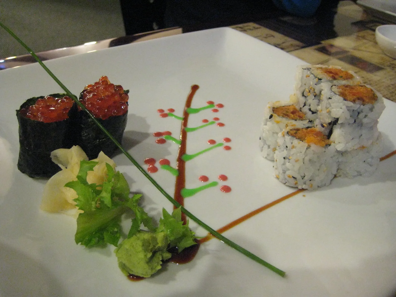 Salmon roe sushi and a spicy roll on a white plate with ginger and wasabi. The photo was not taken in Cary.