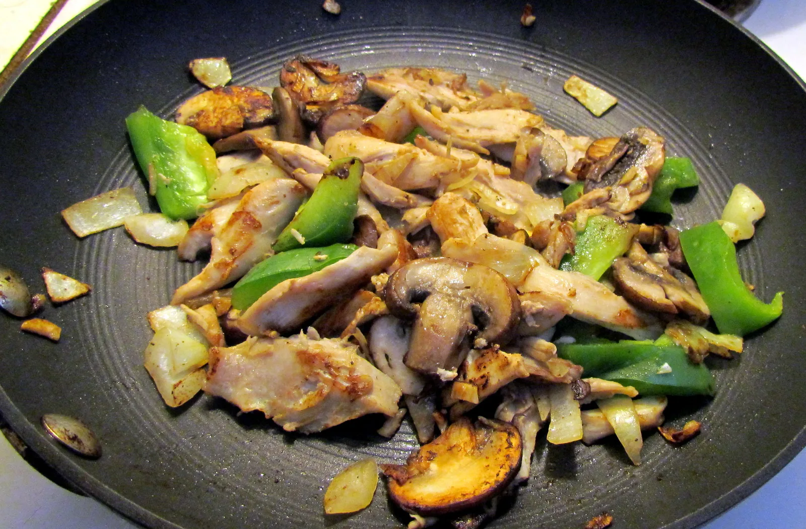 Chicken, mushrooms, onions and green peppers cooking in a skillet, photographed in Cary.