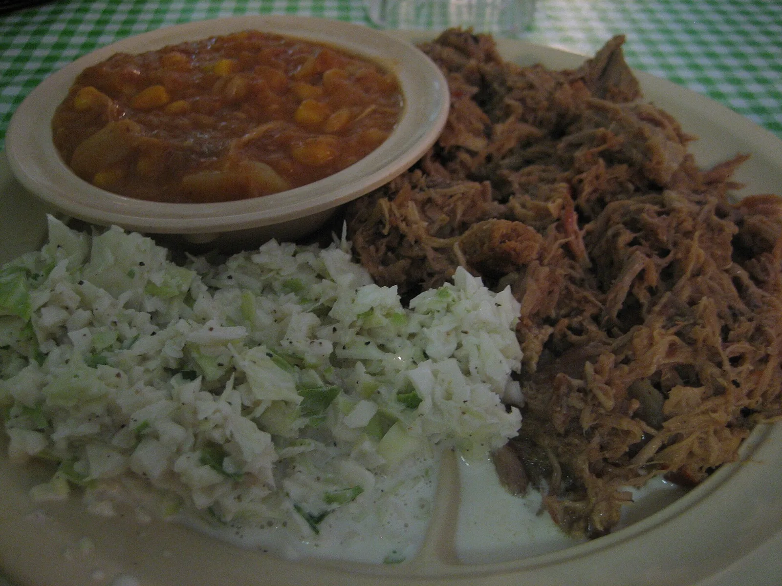 A plate of pulled pork barbecue with coleslaw and a bowl of Brunswick stew. The photo was not taken in Cary.