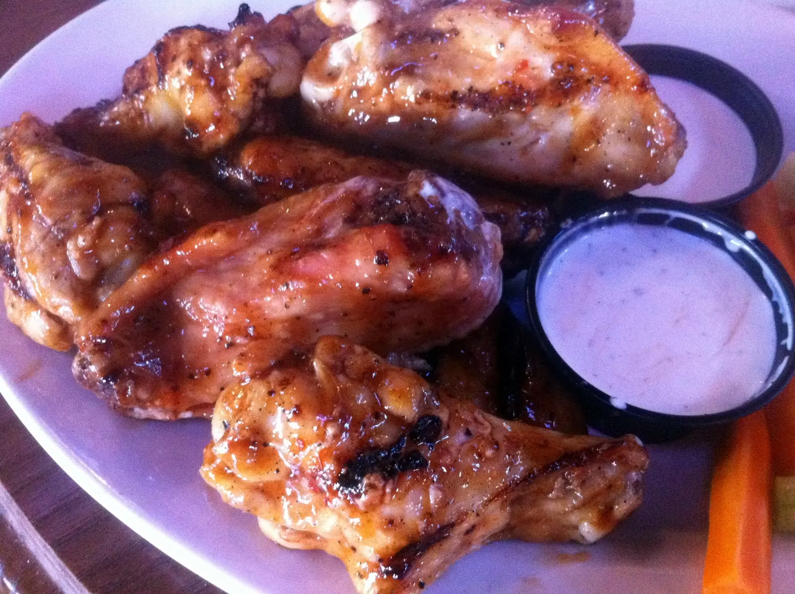 A plate of grilled chicken wings with ranch dressing and carrot sticks at a restaurant in Charlotte. The photo was not taken in Cary.